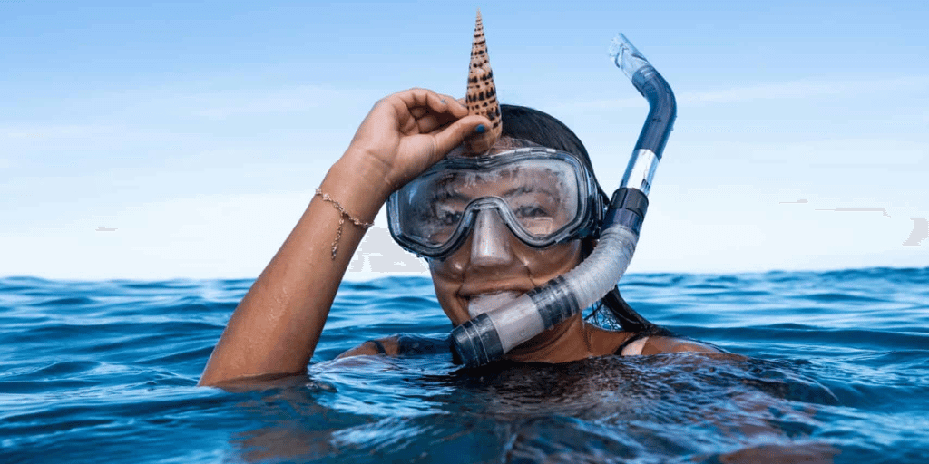 girl playing with shell she found while snorkeling in the ocean